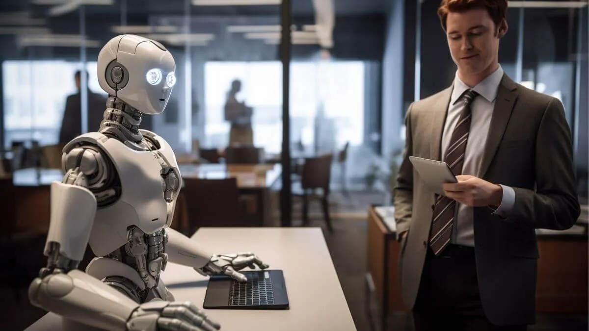 A humanoid robot sits at a desk with a laptop, while a businessman in a suit stands nearby holding a tablet in a modern office setting.