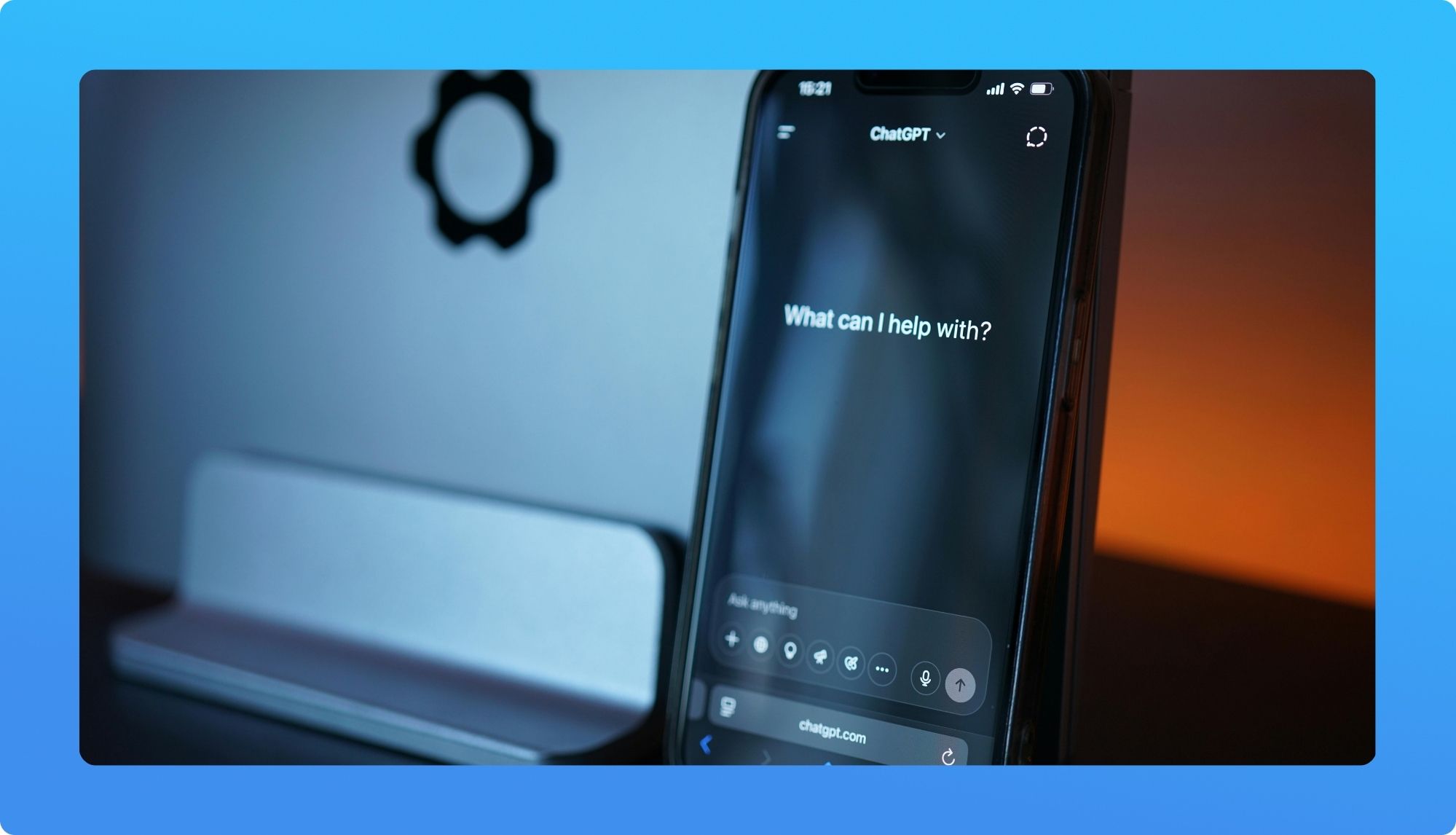 A close-up of a phone displaying the ChatGPT interface with the prompt, "What can I help with?" against a dimly lit background.