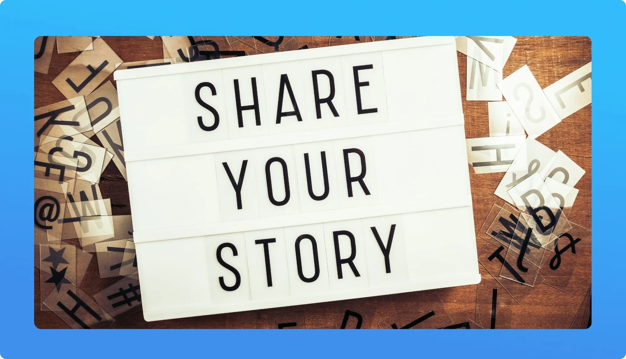 A lightbox displays the phrase "SHARE YOUR STORY," surrounded by scattered letters and symbols on a wooden surface.