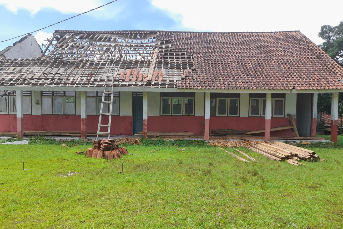 School building with its tiled roof partially torn off by storm damage, under repair