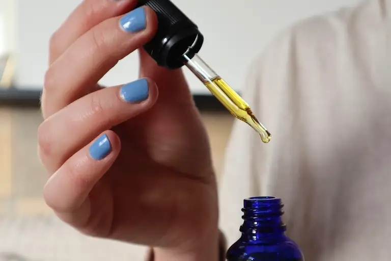 Face oil dropper dispensing oil as part of a simple skincare routine.