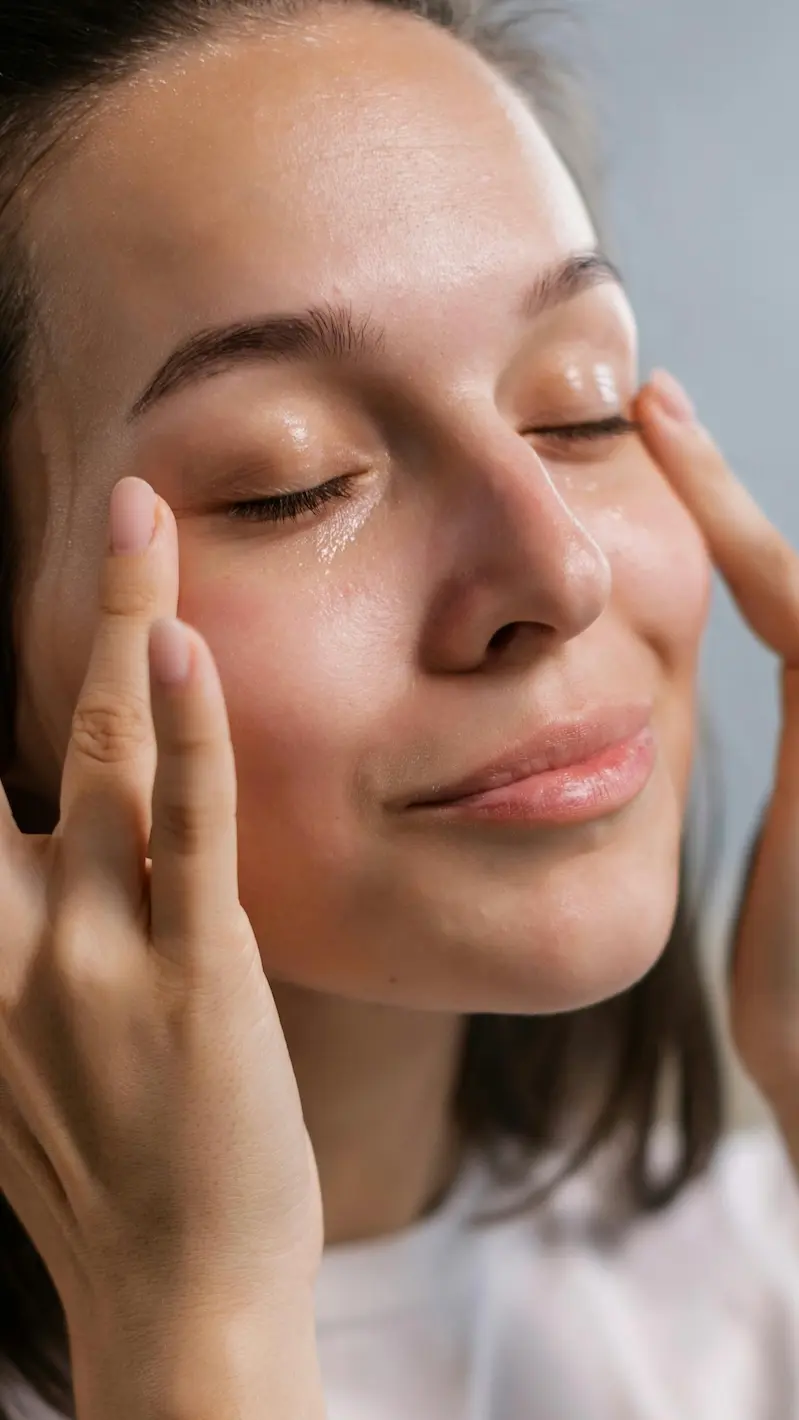 Woman applying skincare with eyes closed, illustrating a calm, grounding skincare ritual focused on touch and presence.