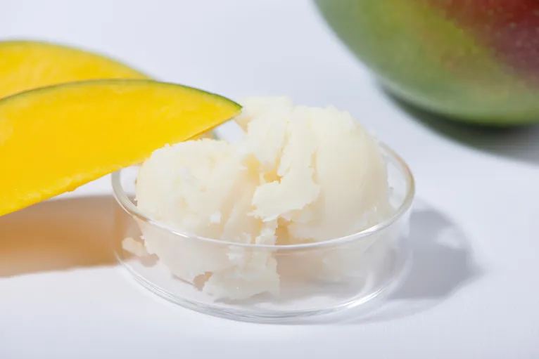 Mango butter, a natural emollient used in hydrating face creams to soften and nourish dry skin.