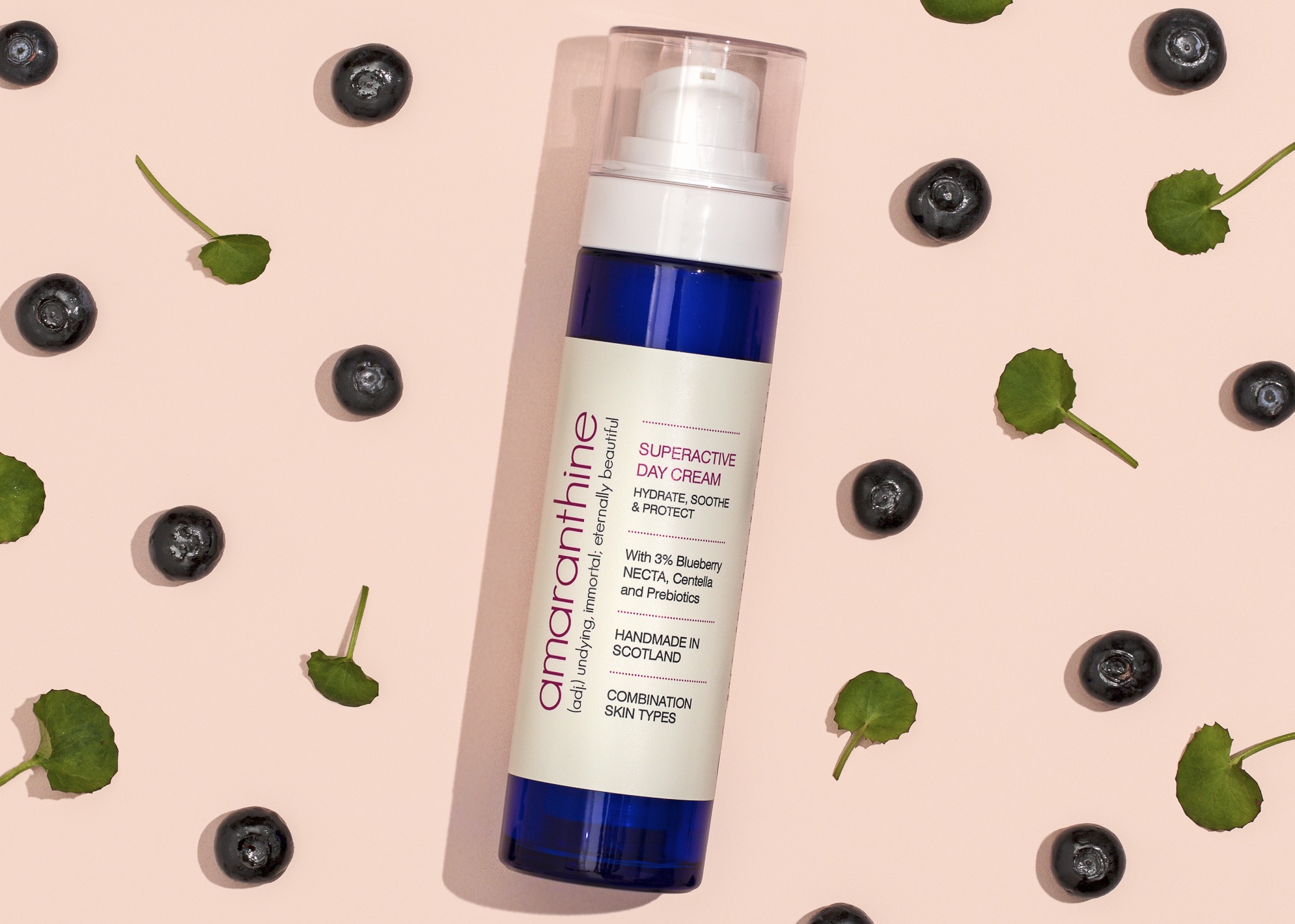 Superactive Day Cream in refillable cobalt blue airless pump bottle with blueberries, featuring upcycled skincare ingredients.