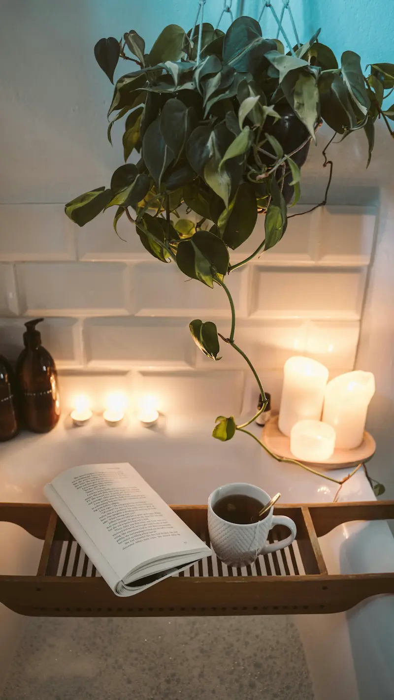 Relaxing bath setup with candles, a book and soft lighting, creating a calm evening self-care ritual