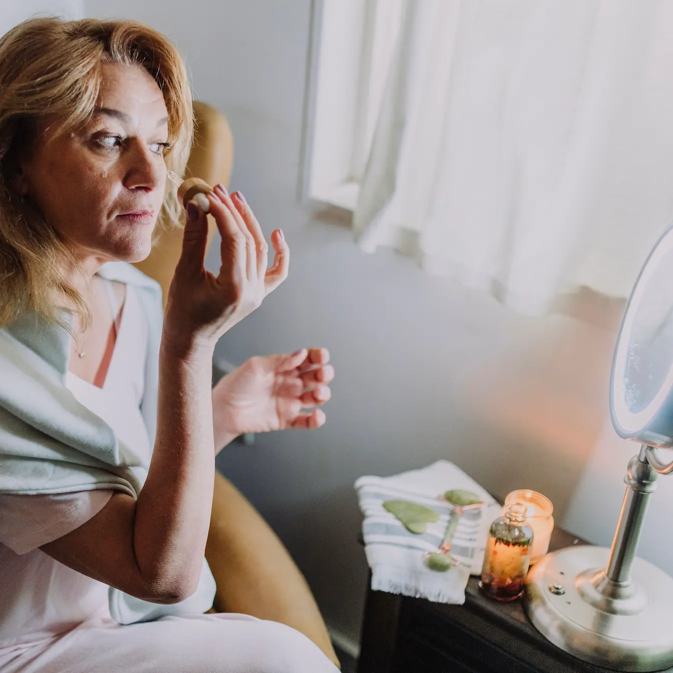 Woman applying a nourishing face oil while caring for skin as it changes with age
