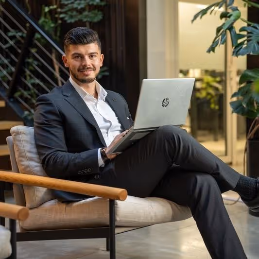 Man in a suit sitting with a laptop in an office