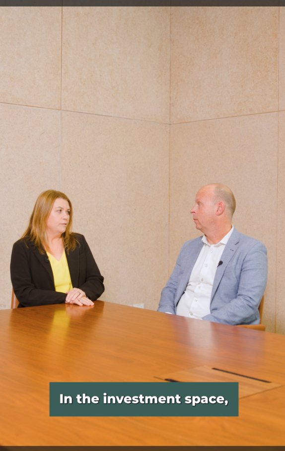 Vinessa and Hayden, seated at a table, discussing NZ investment changes in the last 25-30yrs