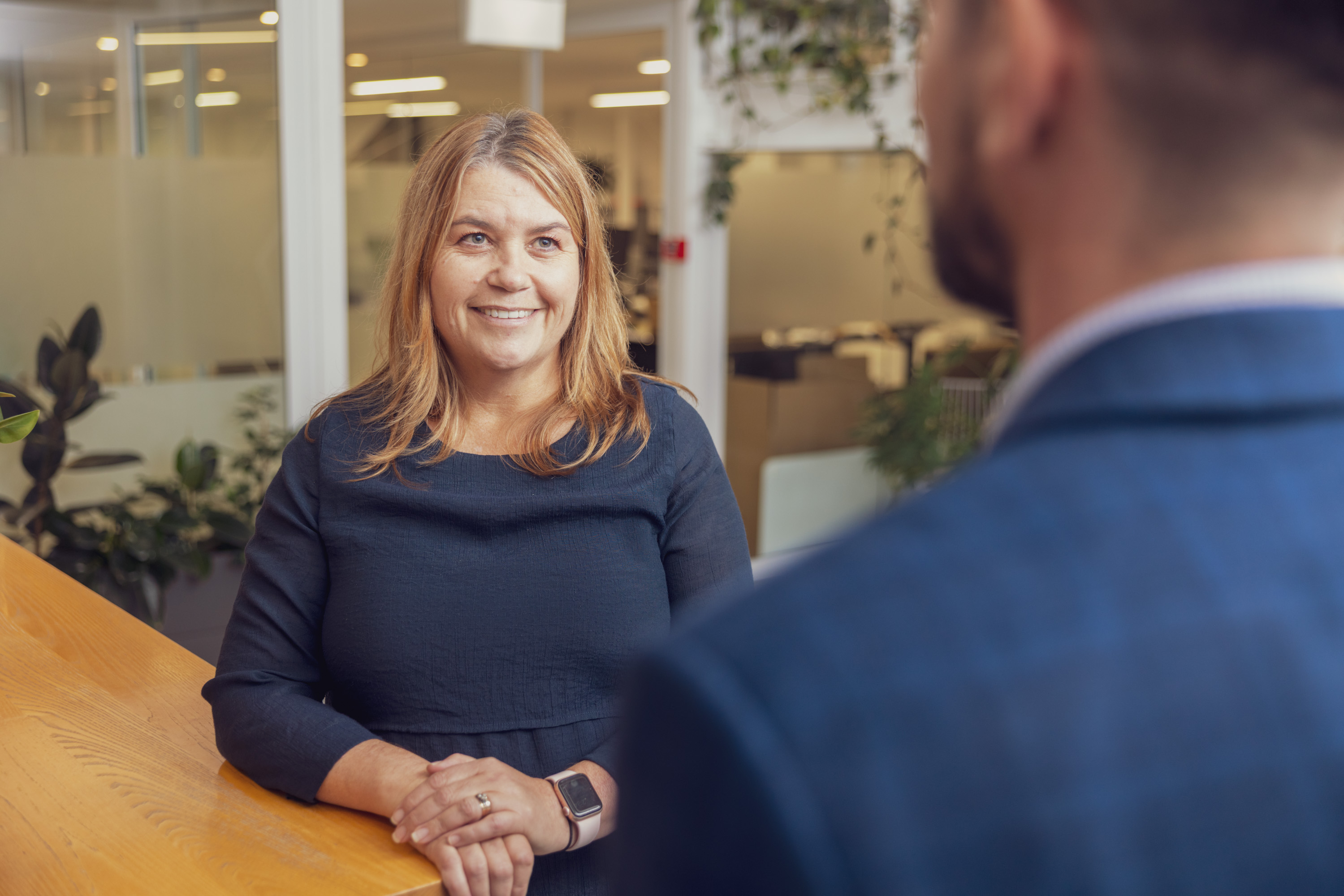 Older New Zealand lady, standing, smiling, reviewing retirement finances with a Become Wealth financial adviser.