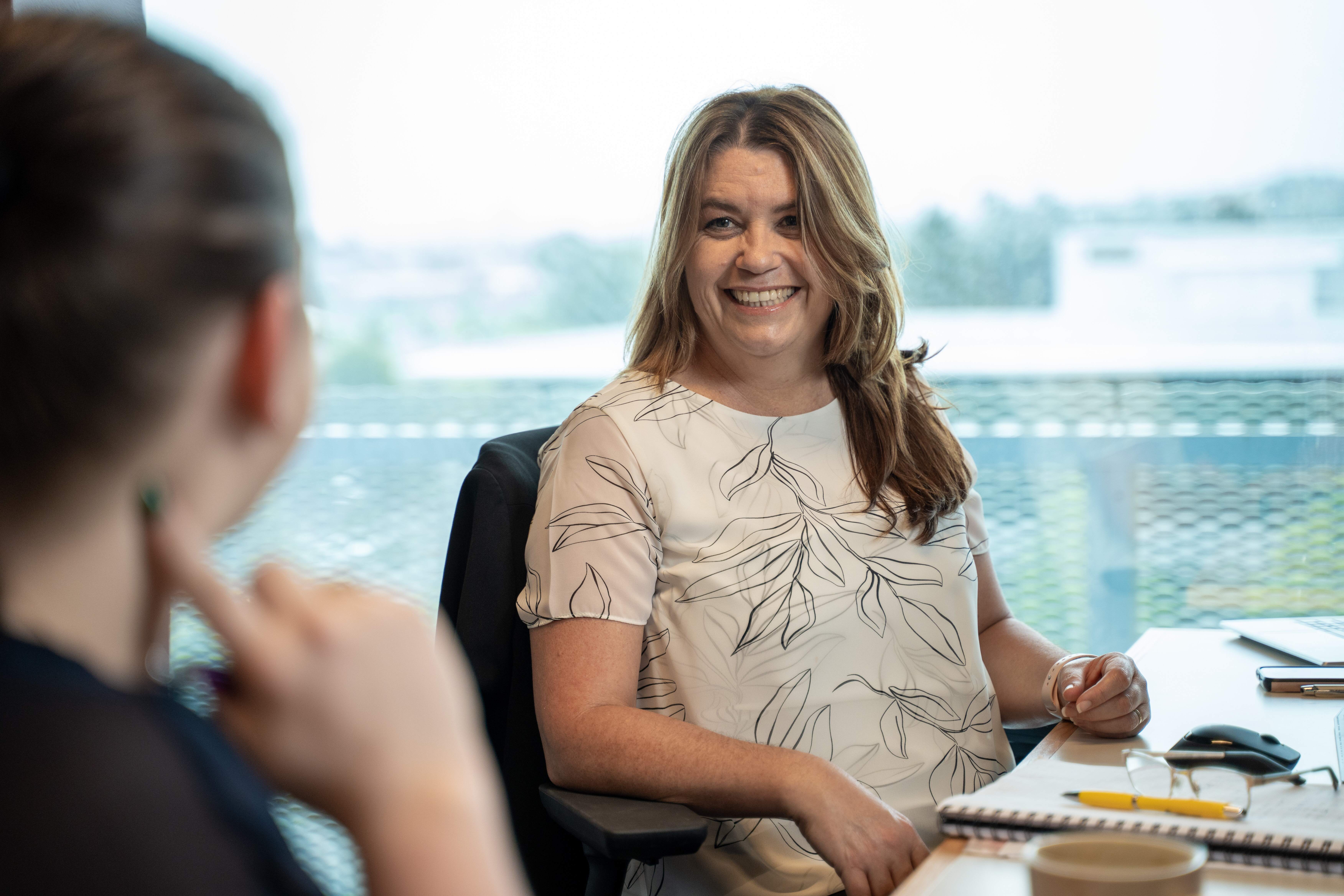 Vinessa, Become Wealth financial adviser, smiling with a client in the office