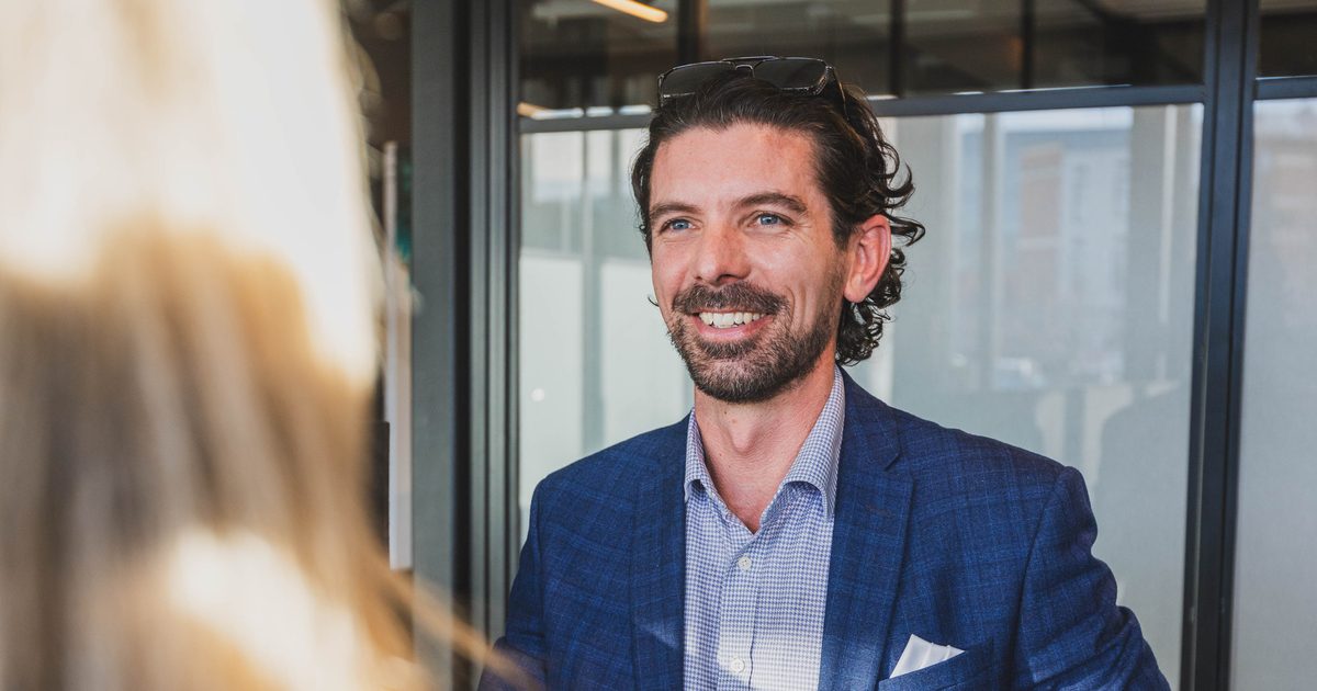 Joseph Darby, CEO of Become Wealth, seated and smiling at a client (over client shoulder)