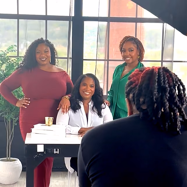 Photographer directing a group brand photoshoot with business owners posed around a desk