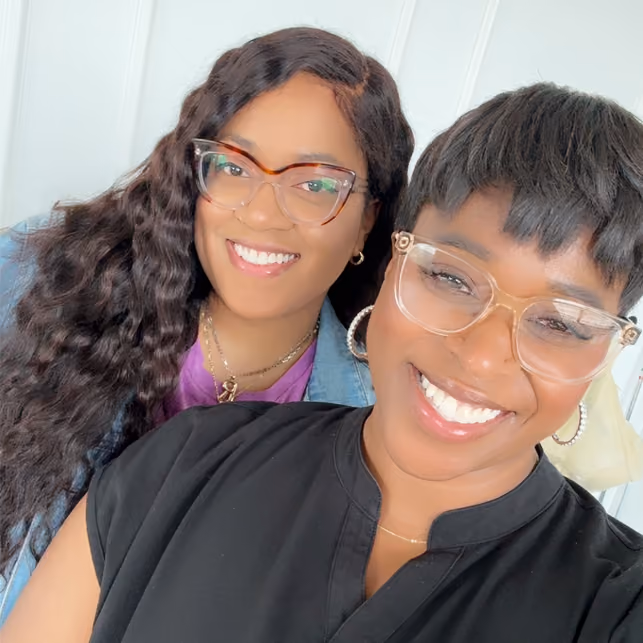 Website strategist and makeup artist smiling together on set during a brand photoshoot