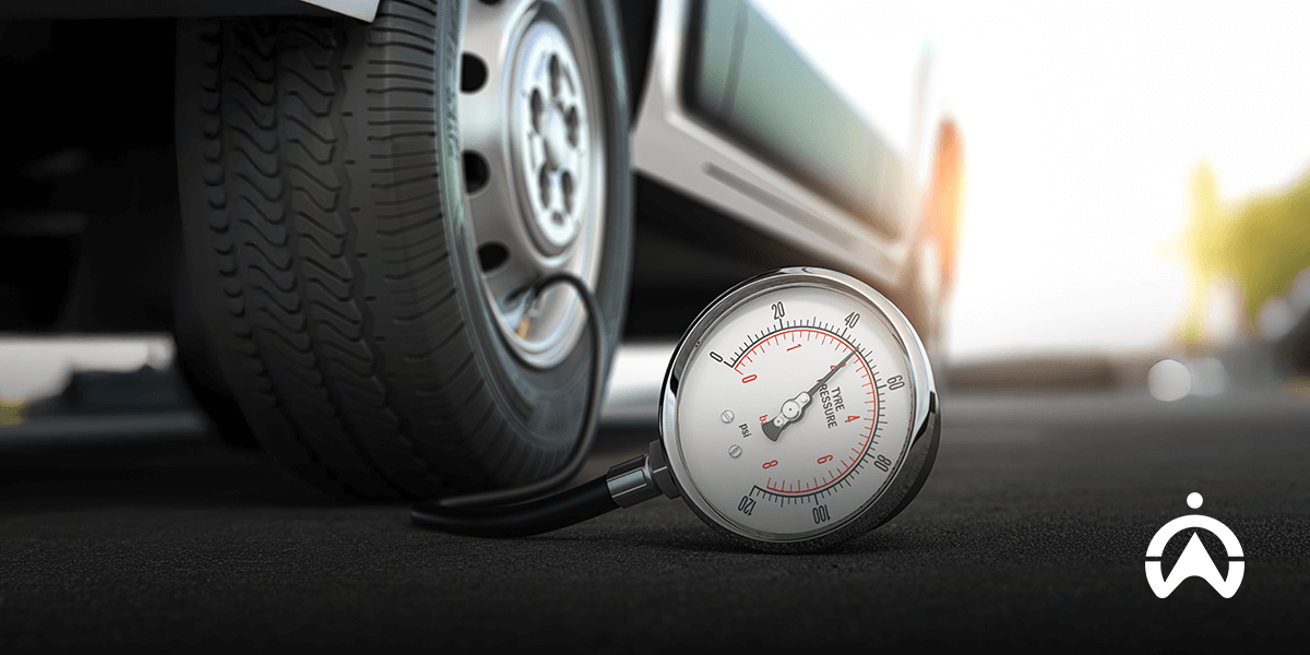 A tire pressure gauge on the ground next to a car tire.