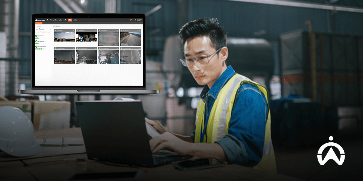 Person in a hi-vis vest working on a laptop with security camera feeds displayed on the monitor.