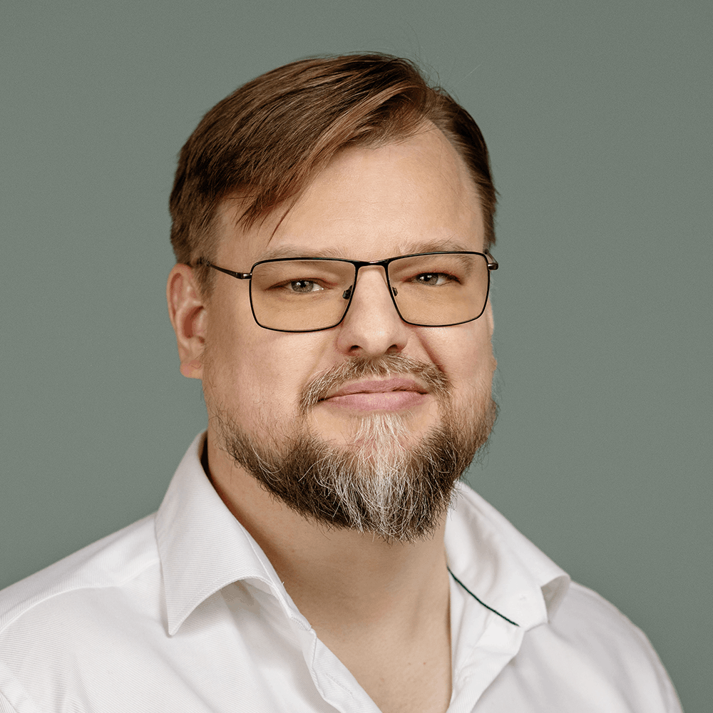 Porträttbild av Andreas Henning. En vit man med glasögon och vit skjorta.