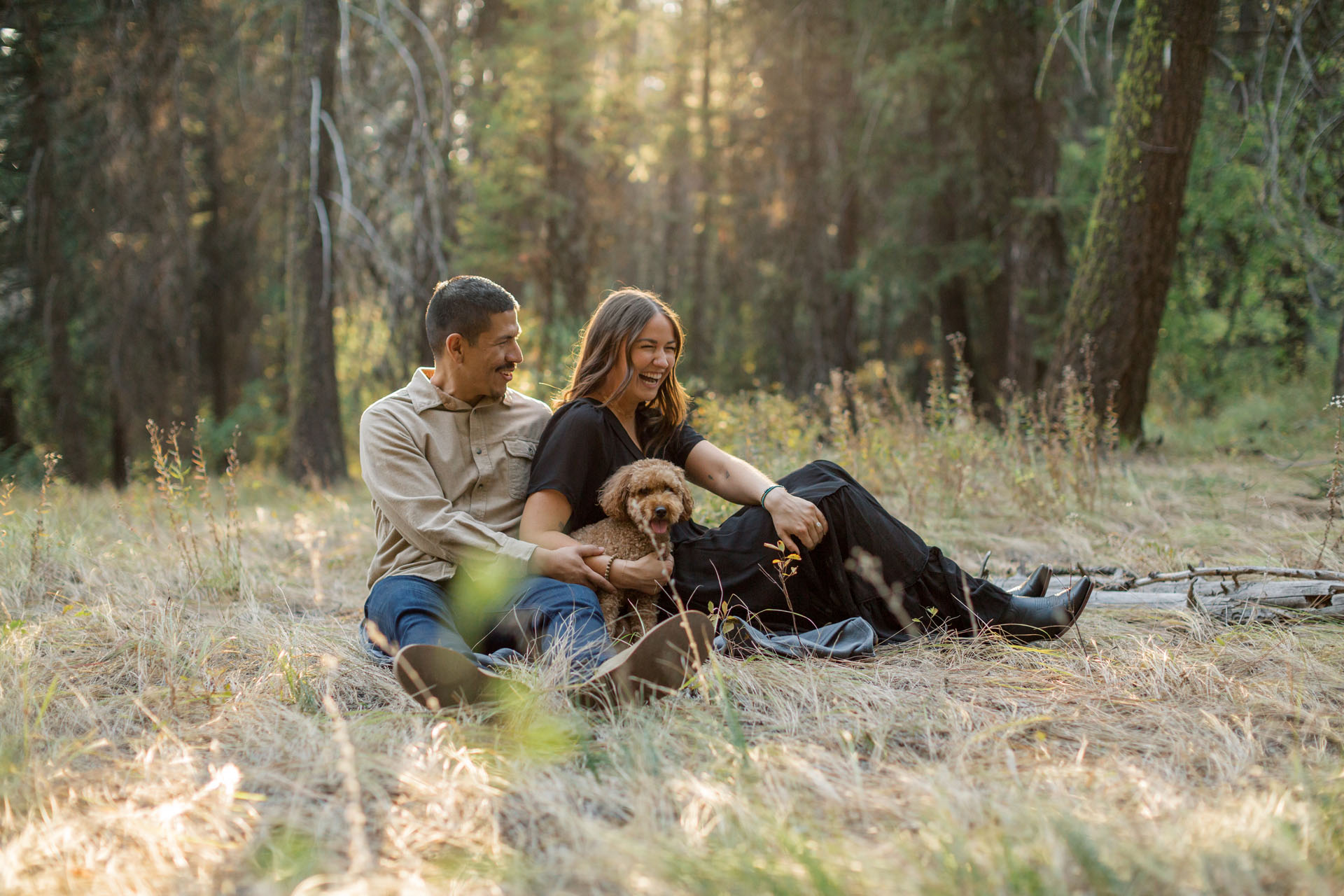 couple sitting with their dog in the forest