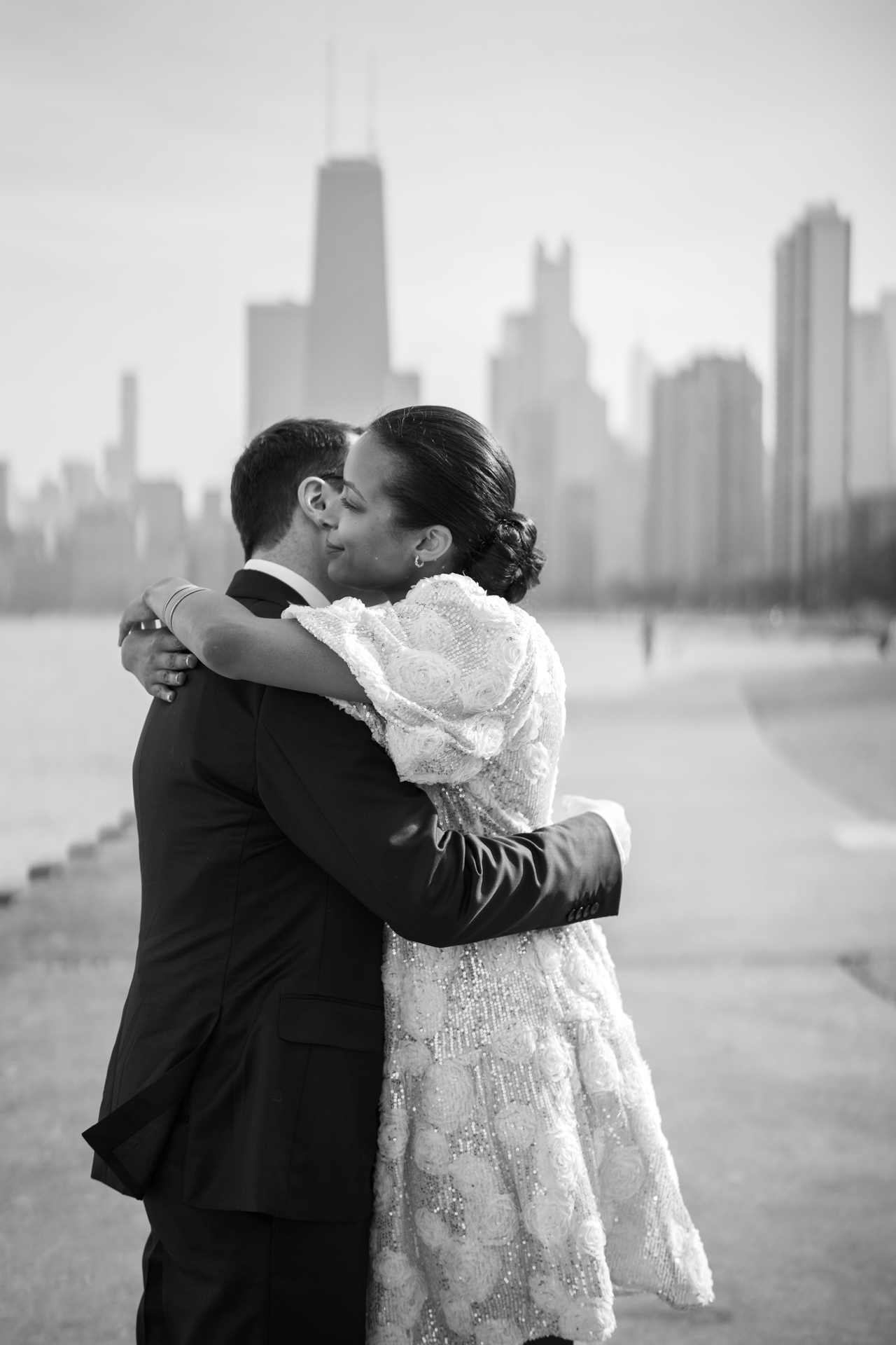 bride and groom hugging with Chicago skyline in the background