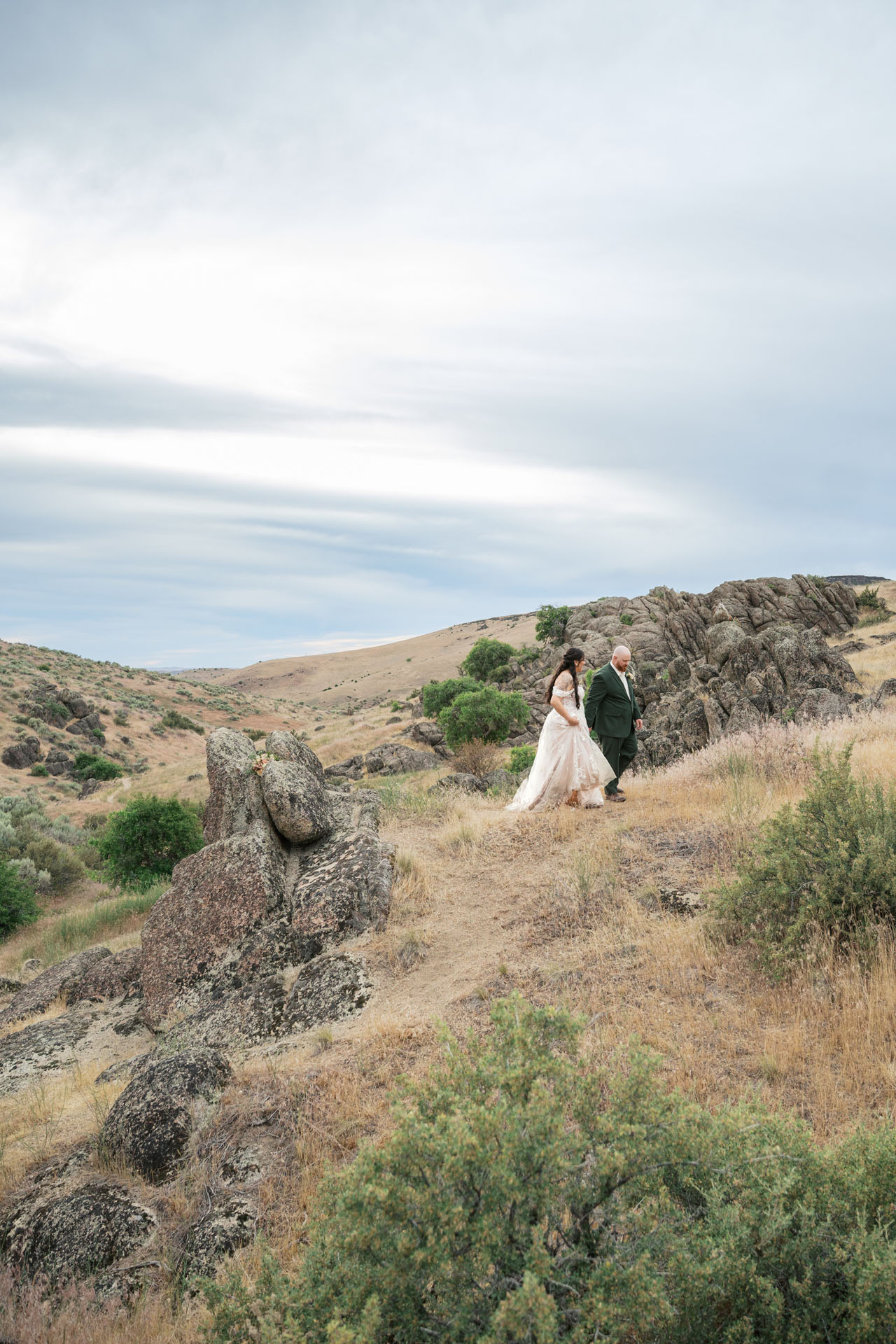 bride and groom walking through rock formations in the boise foothills
