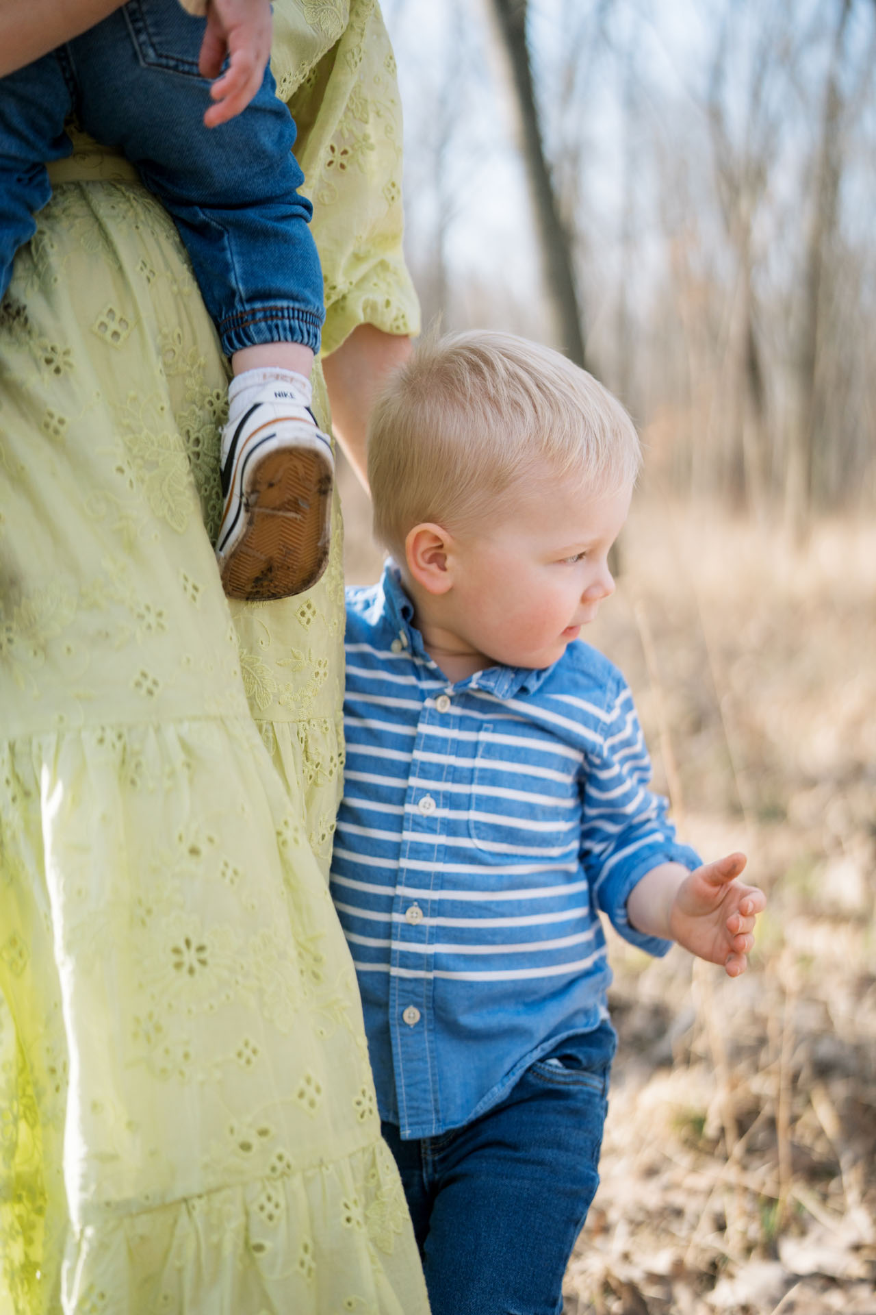 little boy holding onto his mom's leg