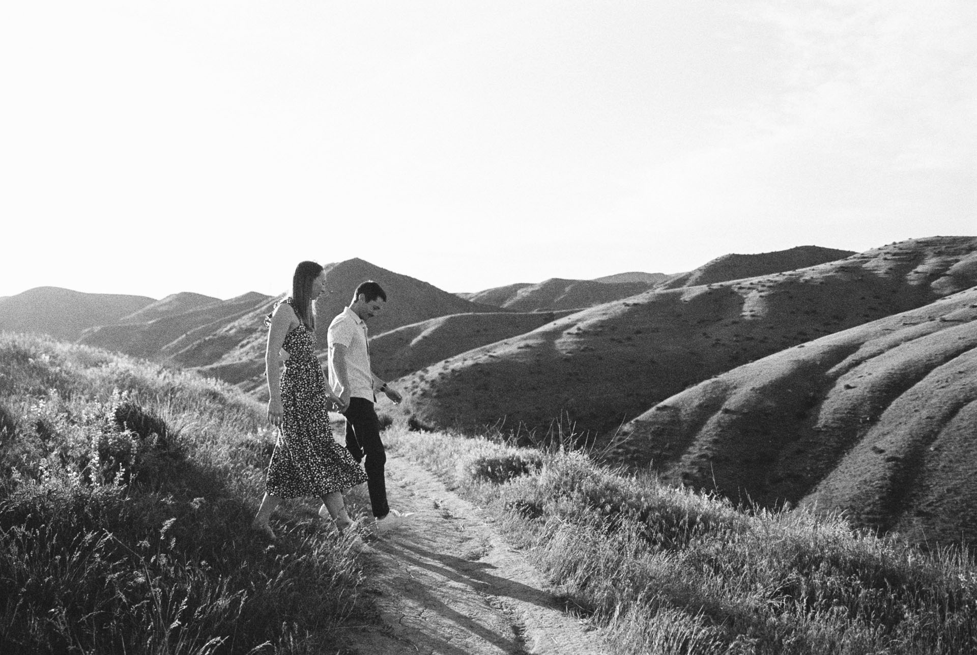 couple holding hands and walking in the foothills