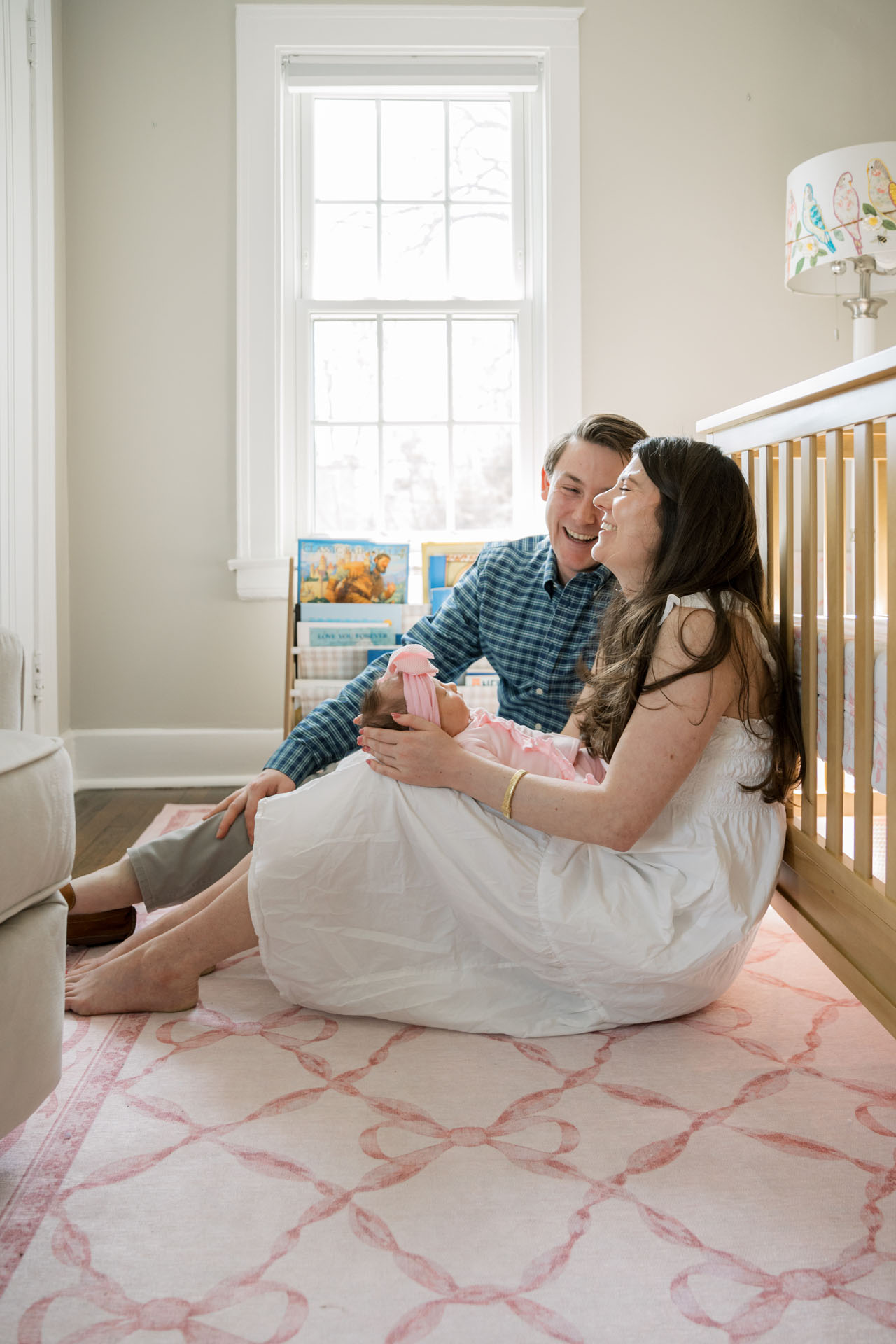 parents sitting on the floor in front of the crib laughing