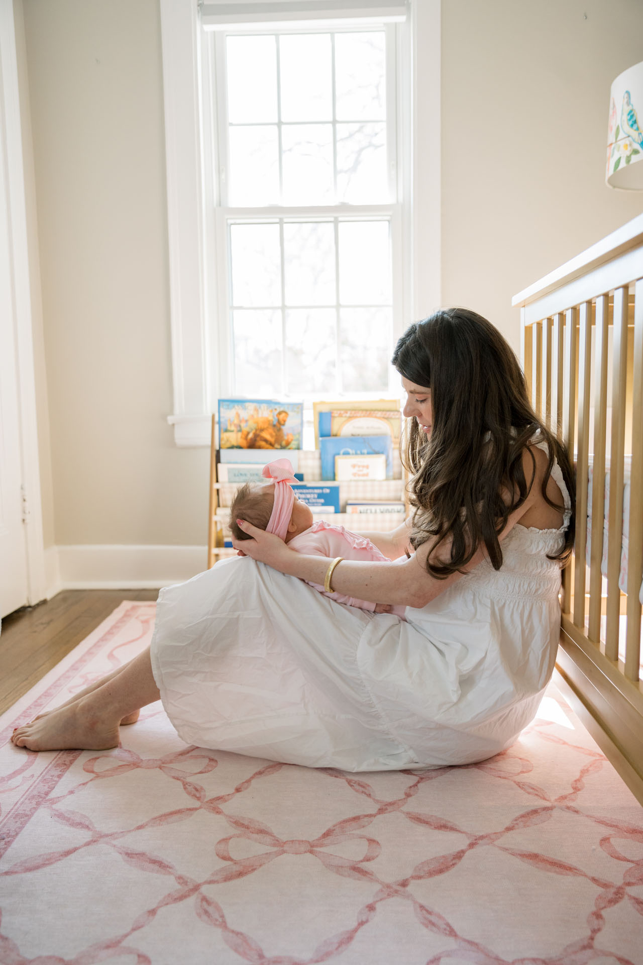 mom talking to her baby while sitting in front of the crib