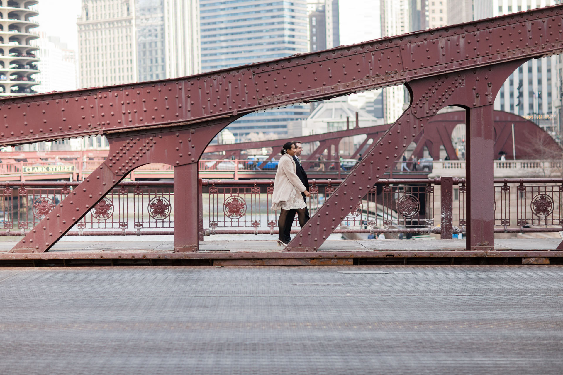 bride and groom walking across a red bridge in Chicago