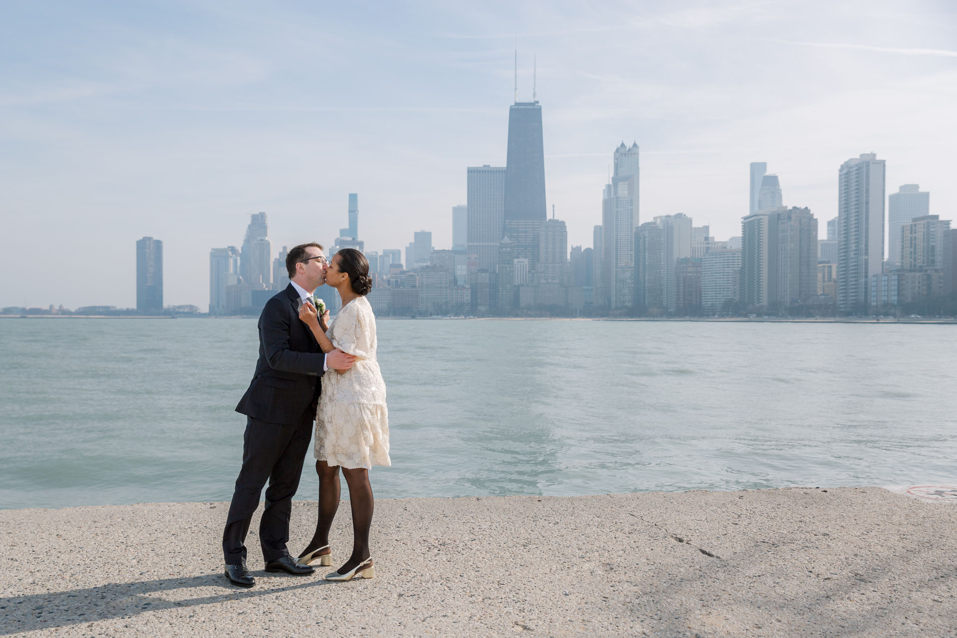bride and groom kissing along the lakefront