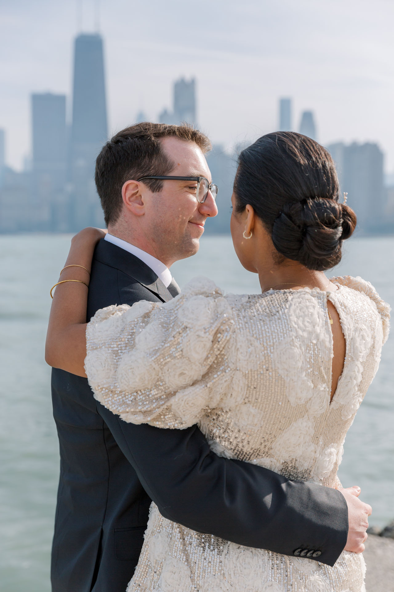 bride's arm around her groom with shadows of the Chicago skyline in the background