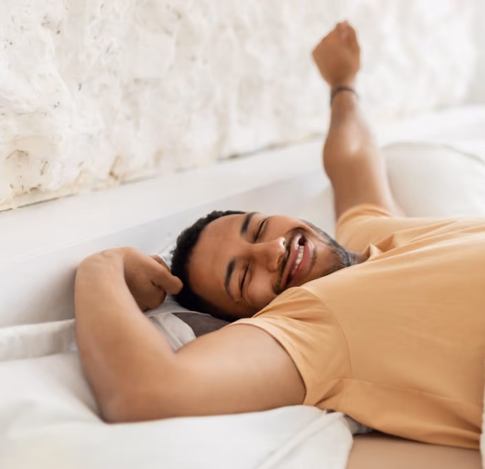 Man smiling as he wakes up rested in bed