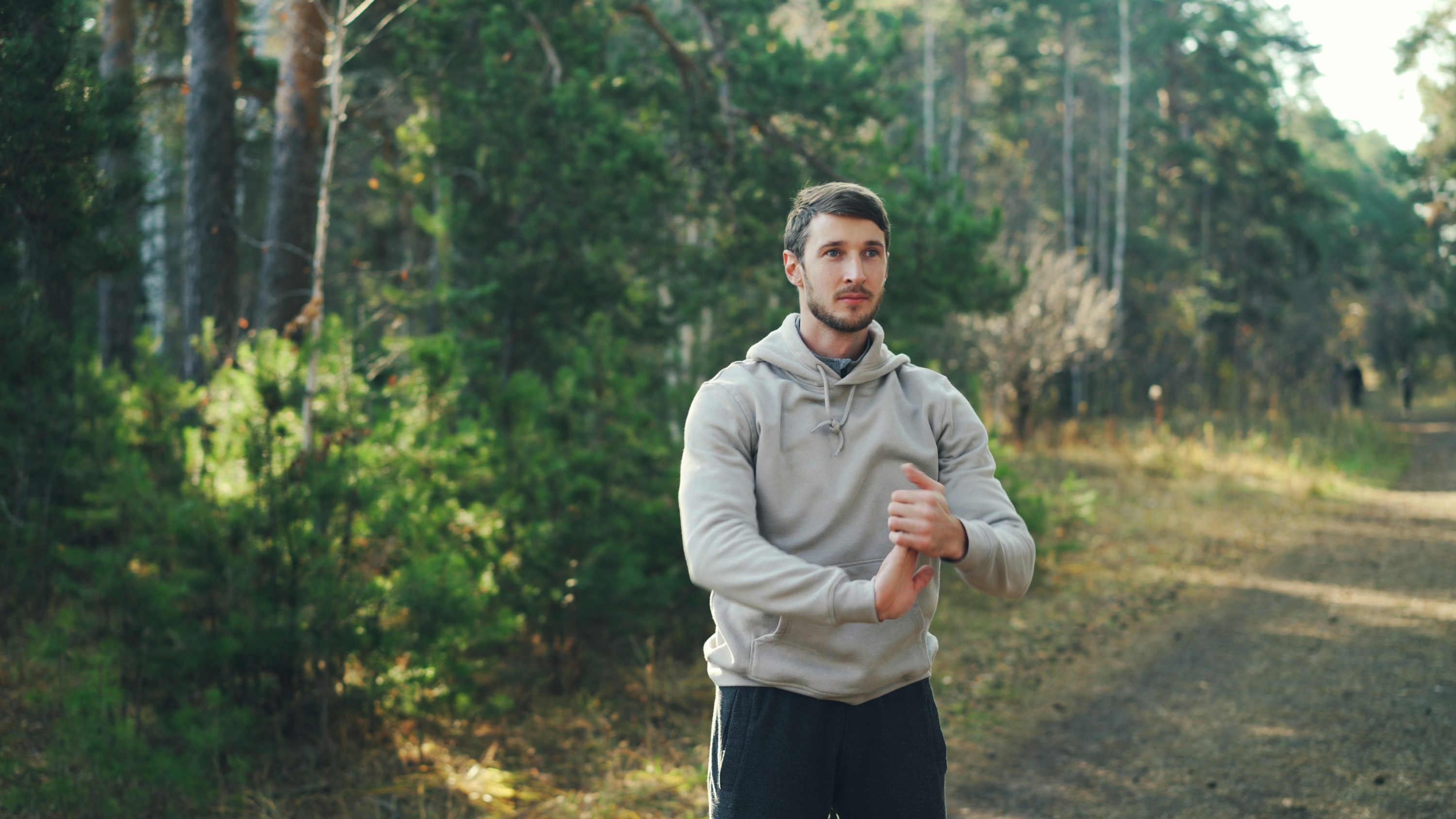 Man stretching outdoors on a forest path as part of a healthy lifestyle.