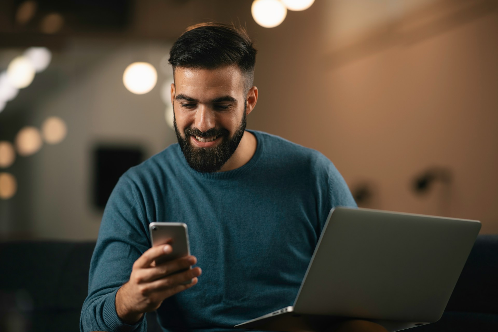 Smiling man using his phone and laptop while starting an online weight loss consultation