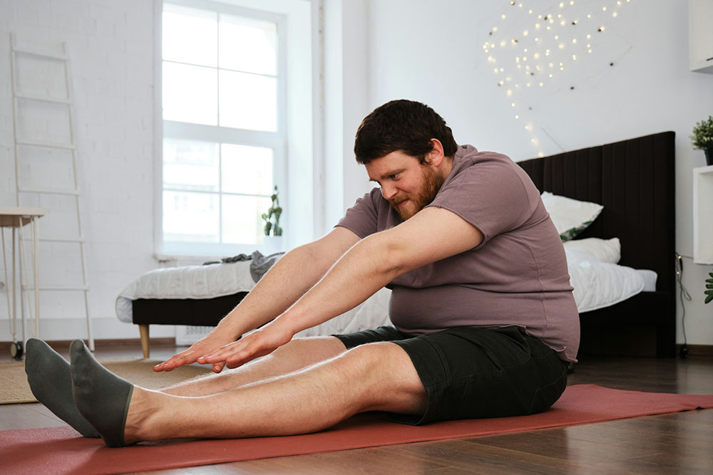 Man stretching at home as part of a weight loss and wellness routine