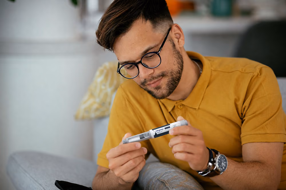 Man examining a Wegovy injection pen while seated at home.