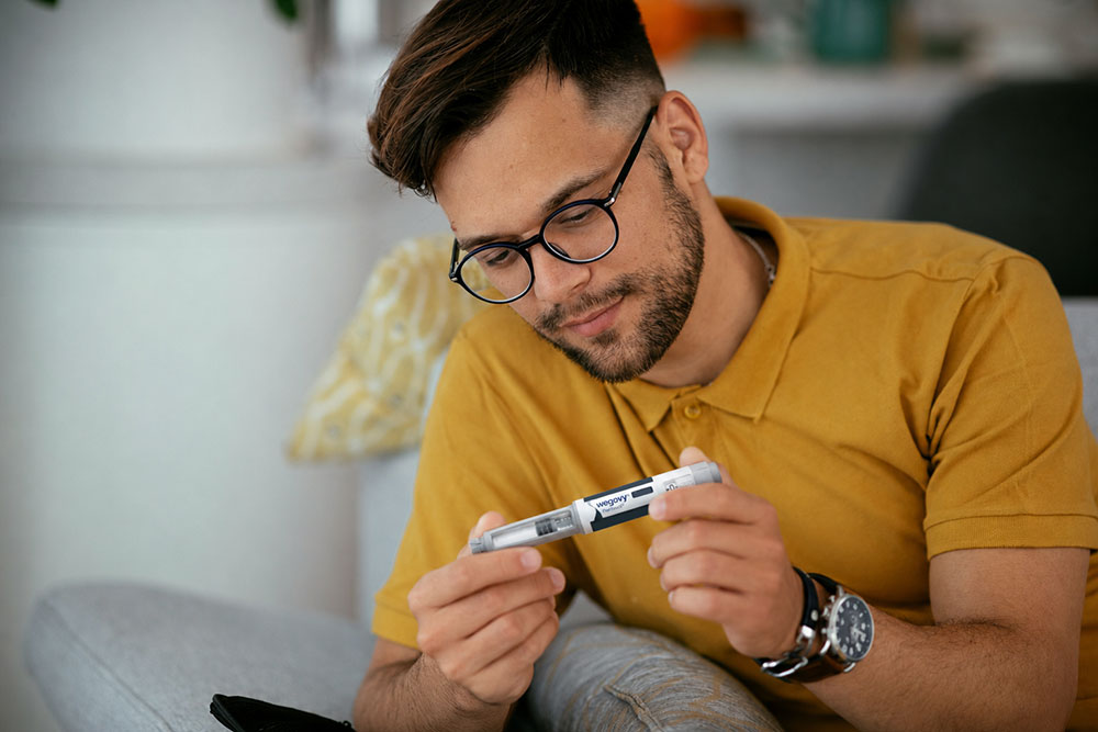 Man examining a Wegovy injection pen while seated at home.
