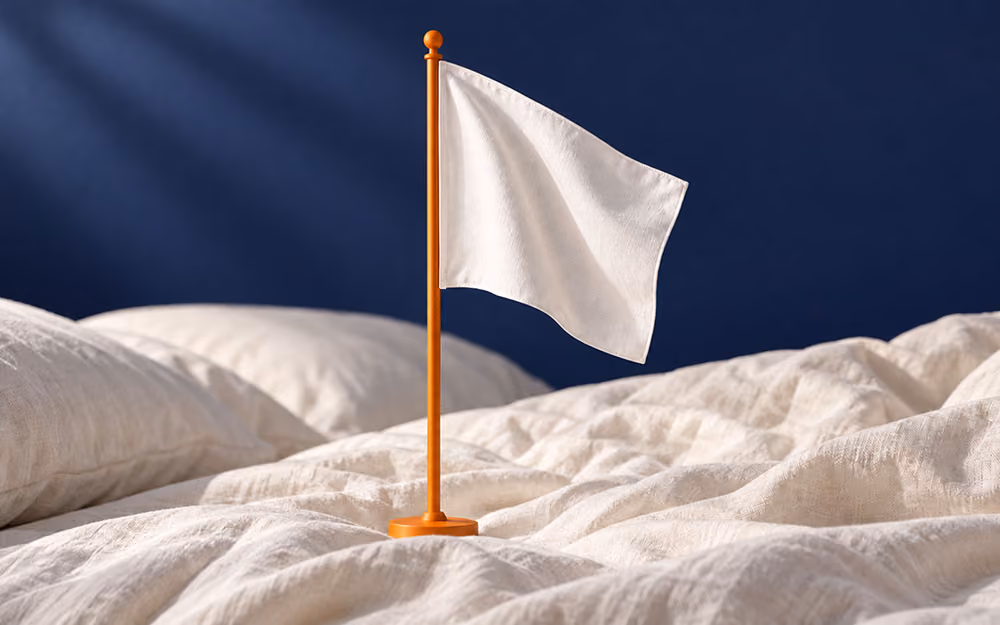 White flag on an orange pole standing upright on ivory bedding against a navy background.