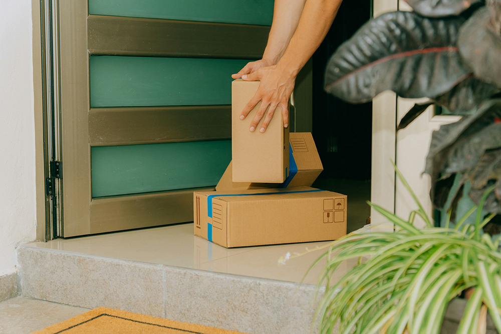 Hands placing delivery boxes on a front doorstep, representing prescription home delivery