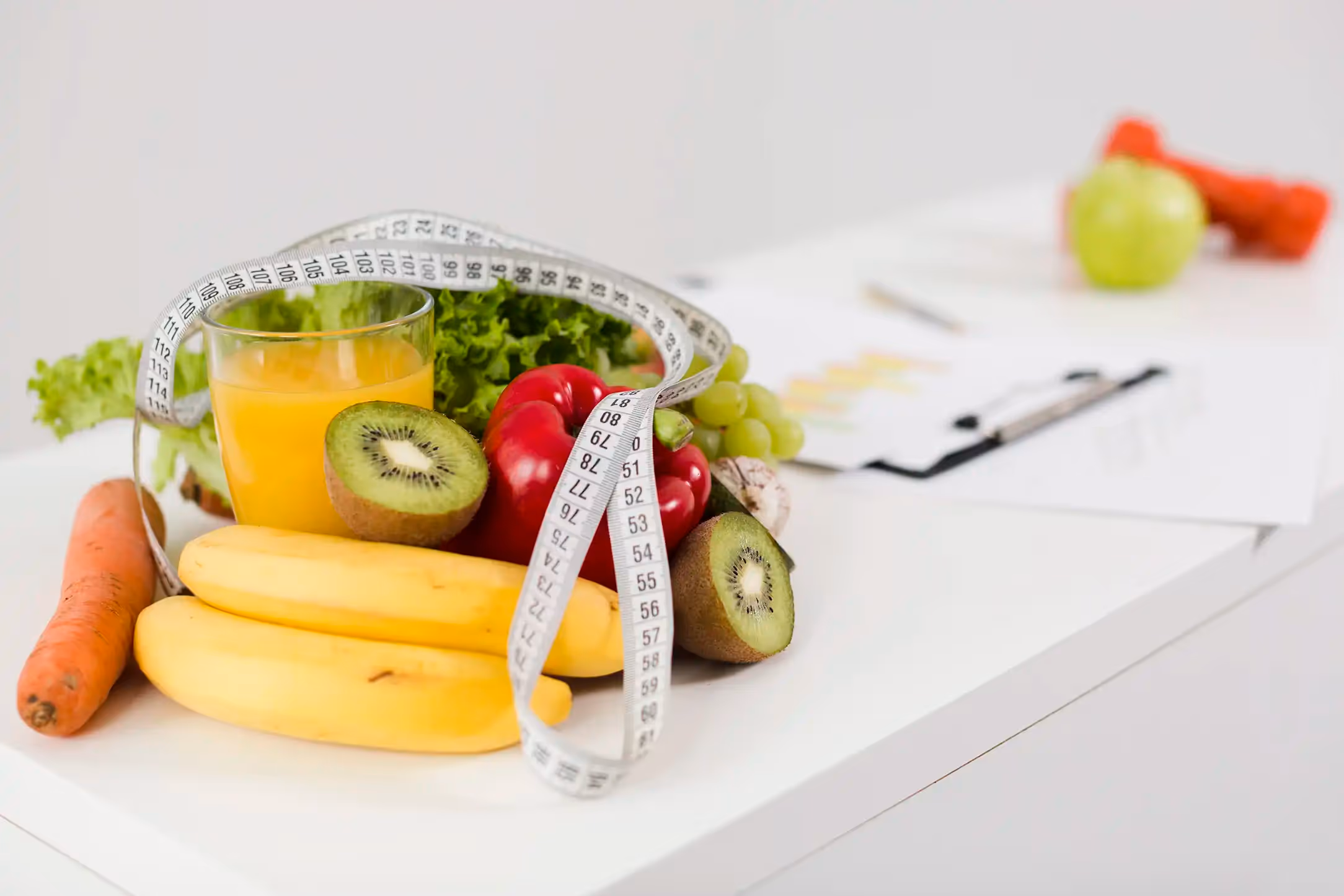 some fruits on the table with a writing board and glass of orange juice