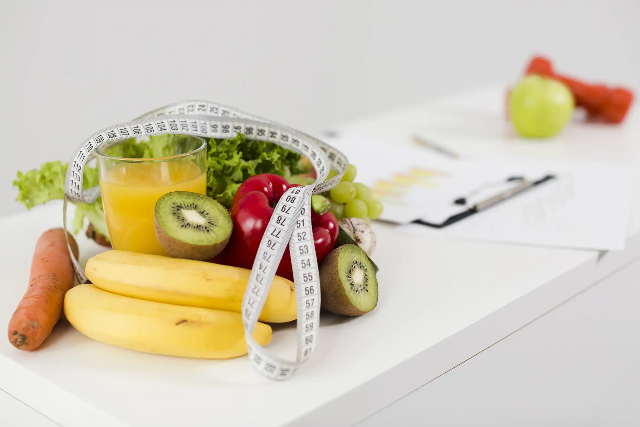 some fruits on the table with a writing board and glass of orange juice