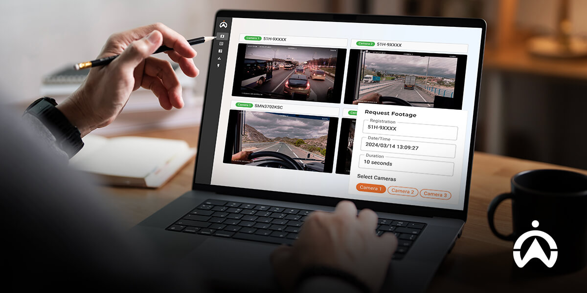 A person using a laptop to request vehicle camera footage, with traffic and road images displayed on the screen.