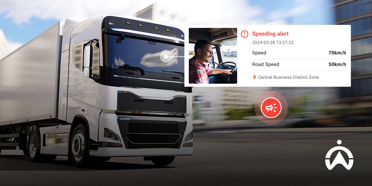 A large white truck is in motion on a city street, with a notification displaying a speeding alert and relevant details.