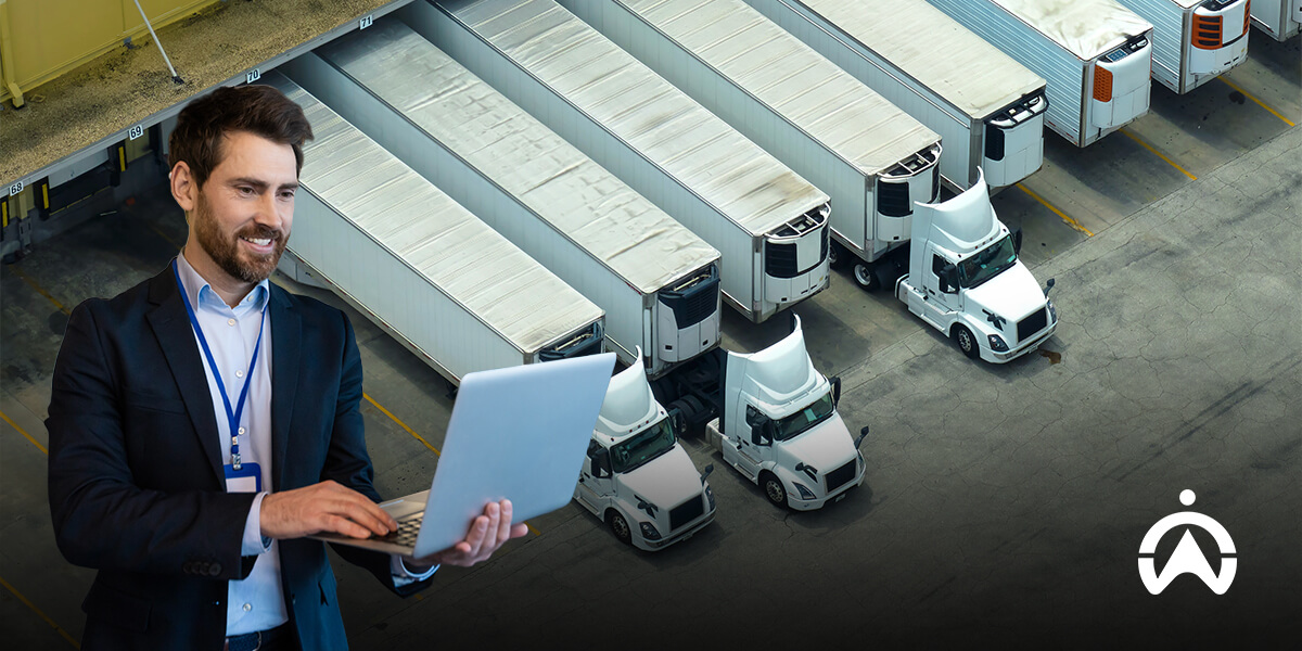 Cartrack advanced fleet management features with person using laptop to oversee parked trucks.