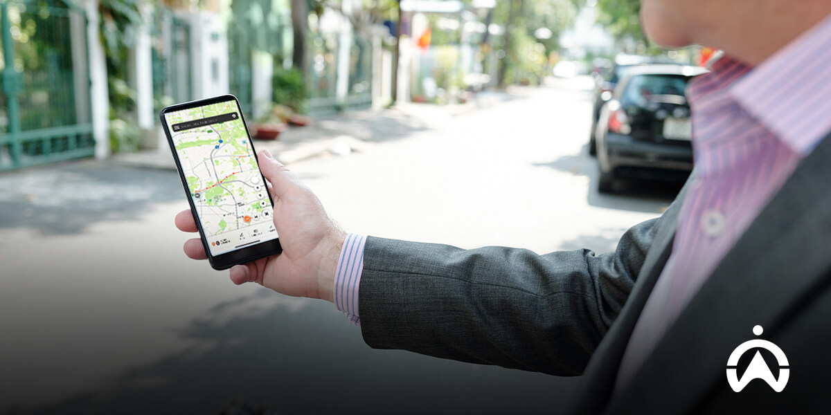 A man holding a phone displaying Cartrack app as most effective GPS tracker.