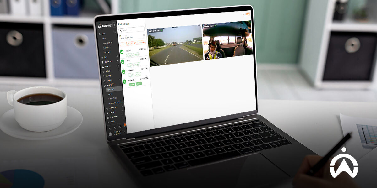 Cartrack dashcam footage on laptop showing live traffic and vehicle interior with coffee cup nearby.