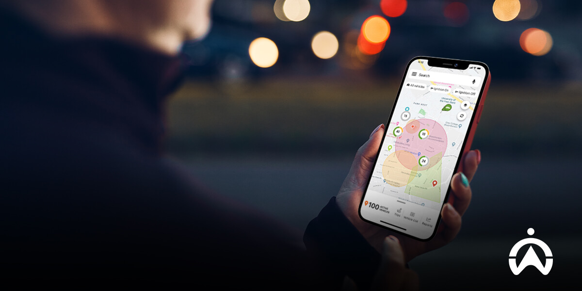 Person using a smartphone with a map showing multiple locations at night, powered by IoT tracking devices.