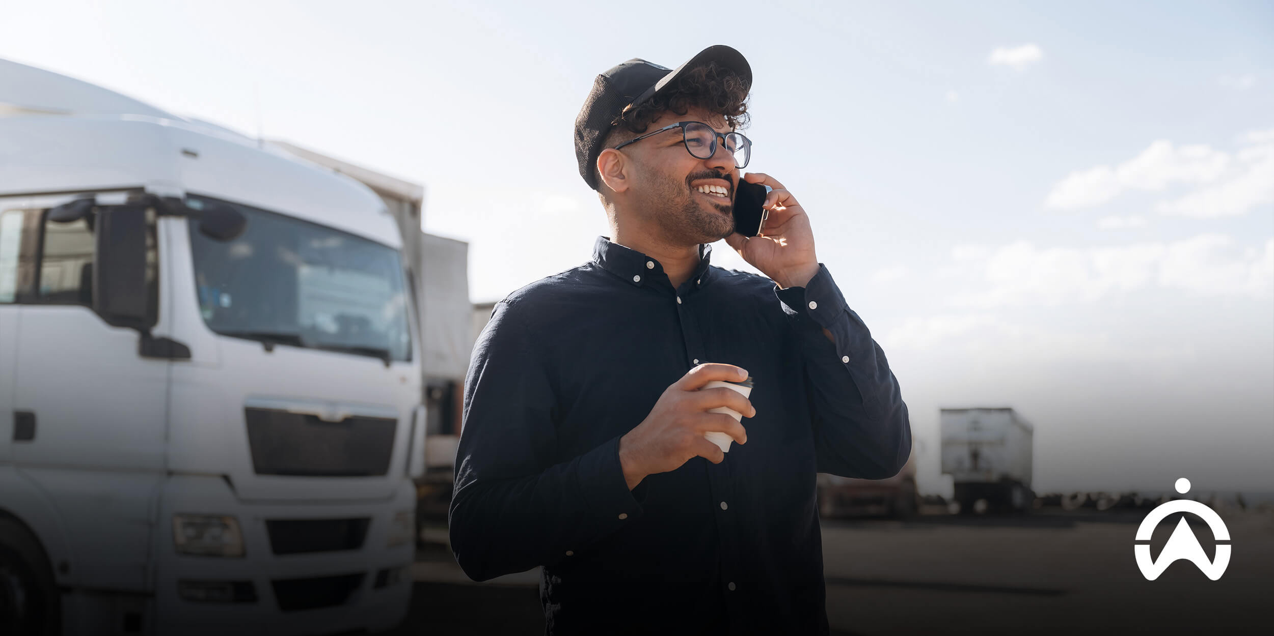 Driver speaking on phone in transport yard, supporting fleet gamification and driver safety initiatives.