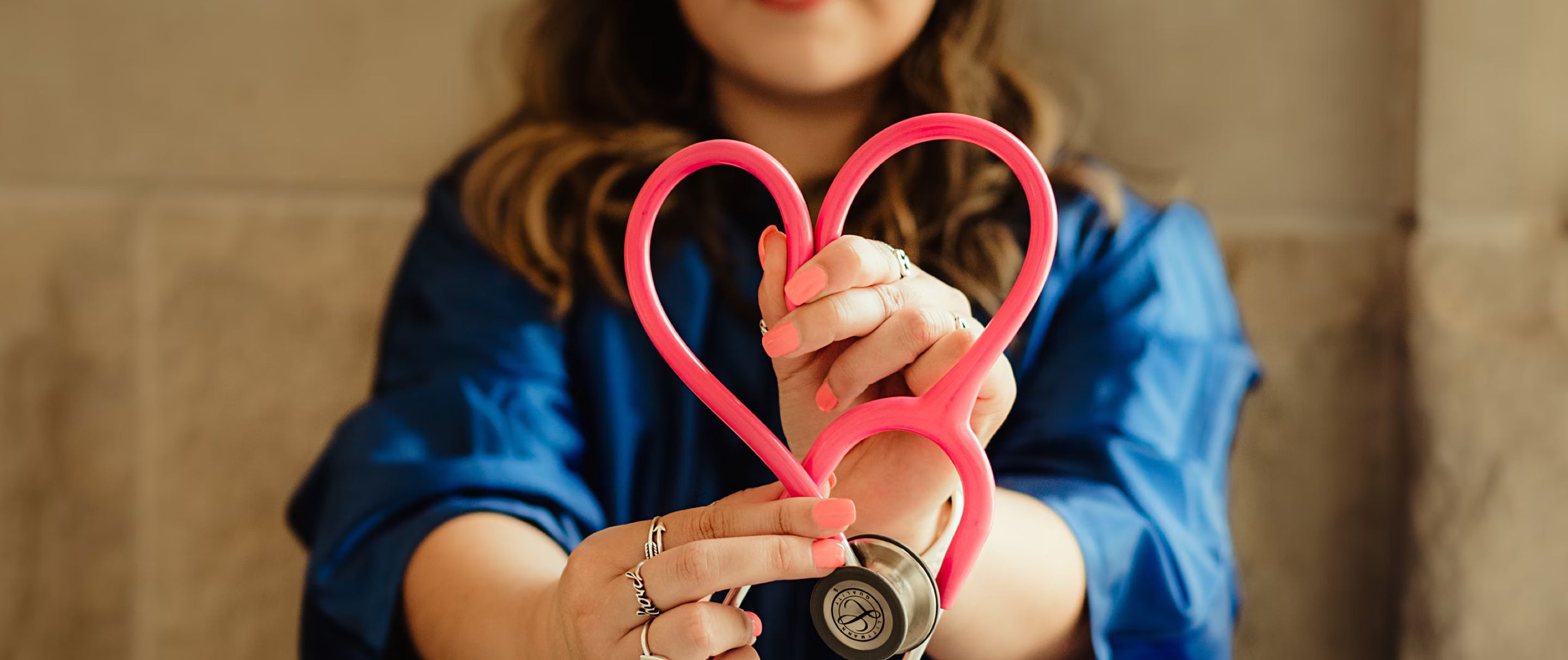 A nurse making a heart shape out of her stethoscope