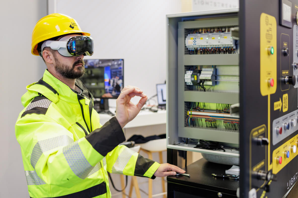 A technician wearing the apple vision pro while controlling the spatial interface and viewing the documentation while working on an electrical panel.