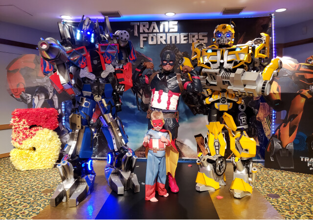 Transformers posing for a photo with Captain America and a child 